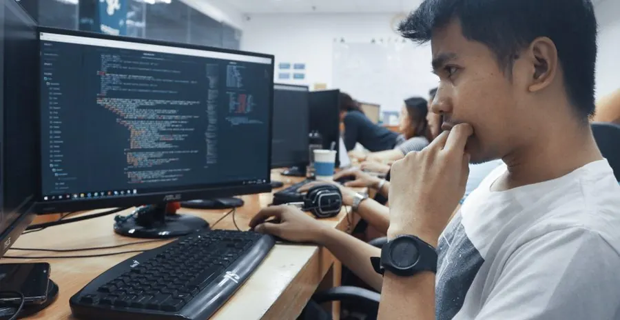 A student writing code at a computer in the training lab